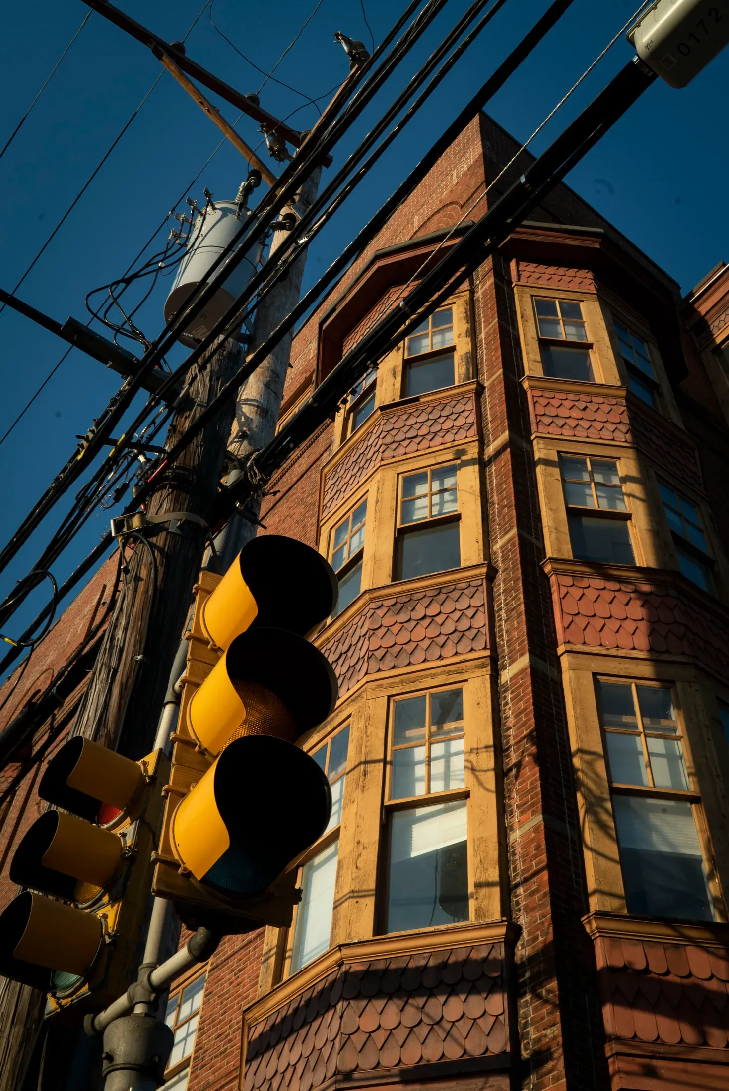Traffic lights and a brick corner framed in afternoon light.