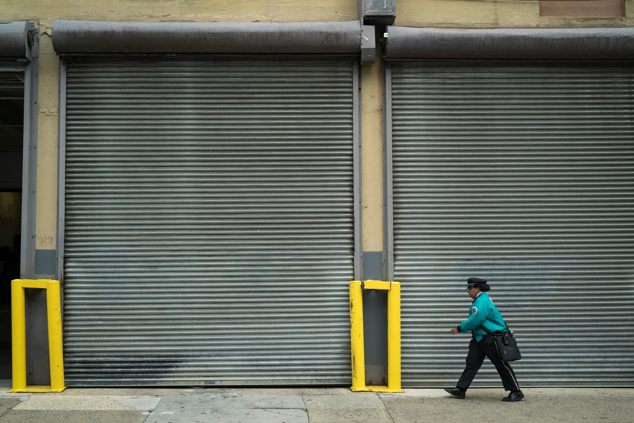 A lone pedestrian walking past industrial shutters.