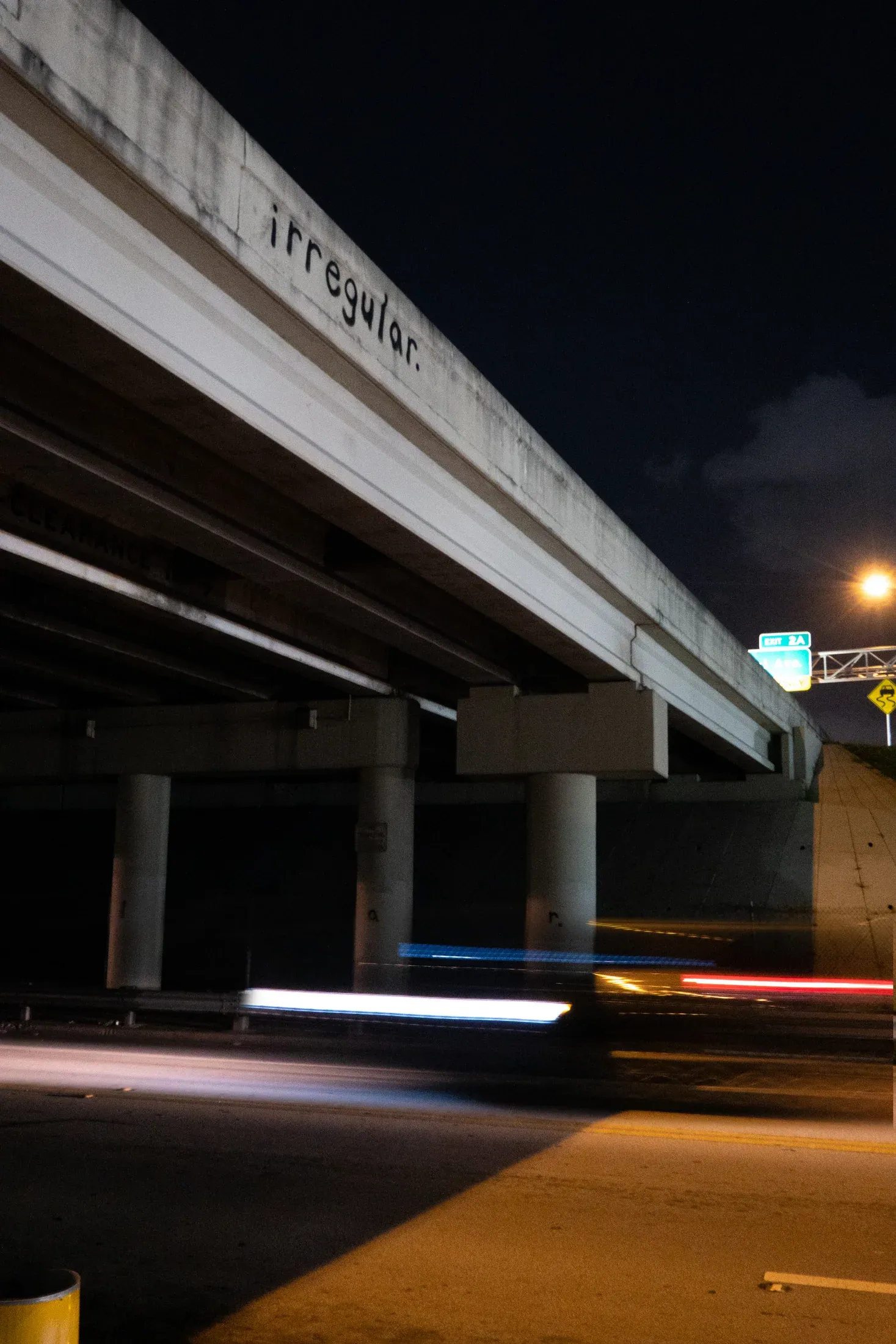 Irregular beneath the concrete overpass after dark.