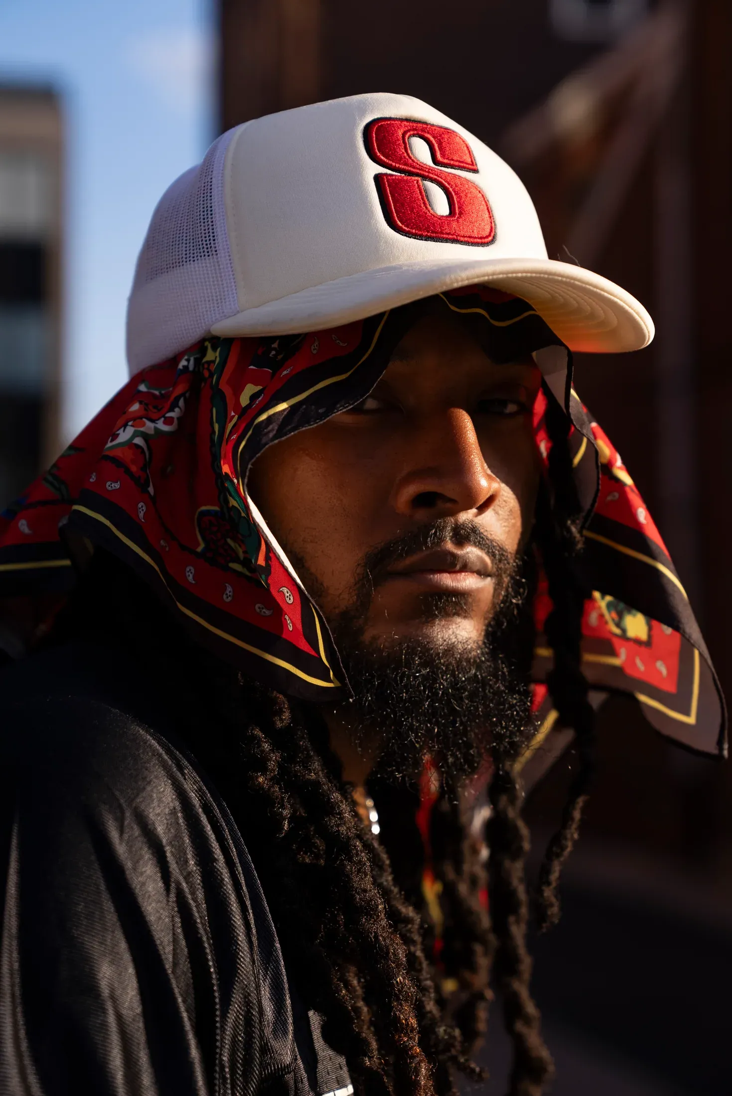Low-key portrait of a musician wearing a red and white cap.