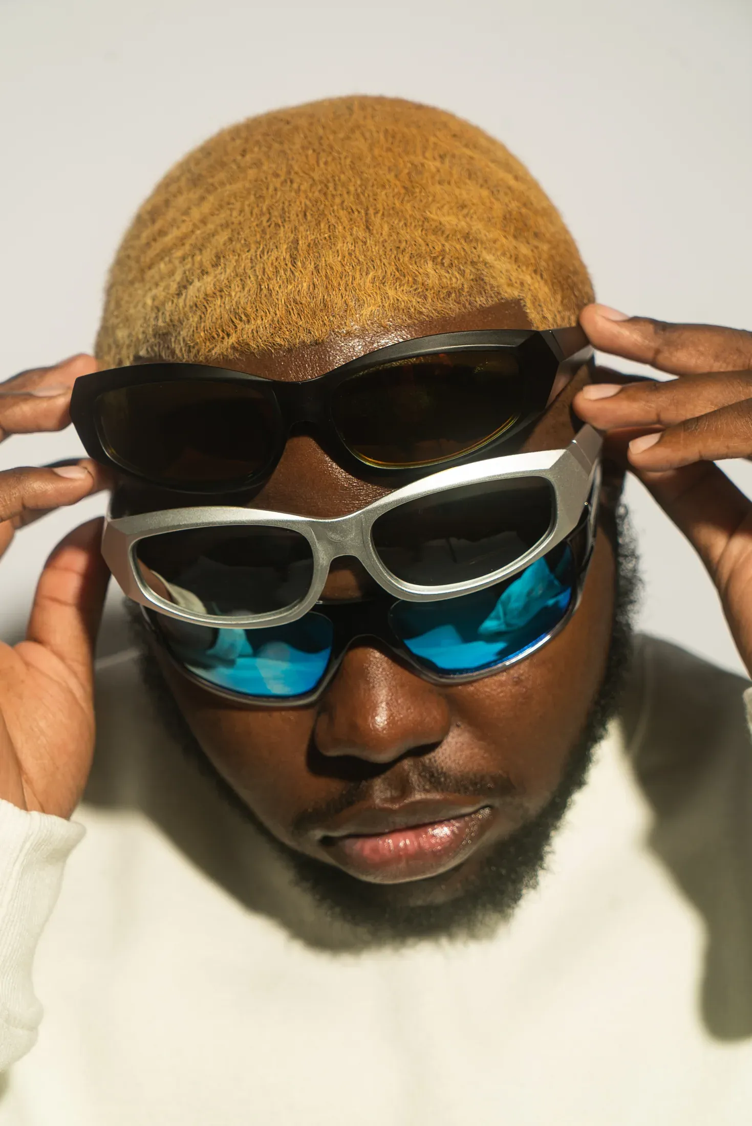 Overhead portrait of a man adjusting layered sunglasses.