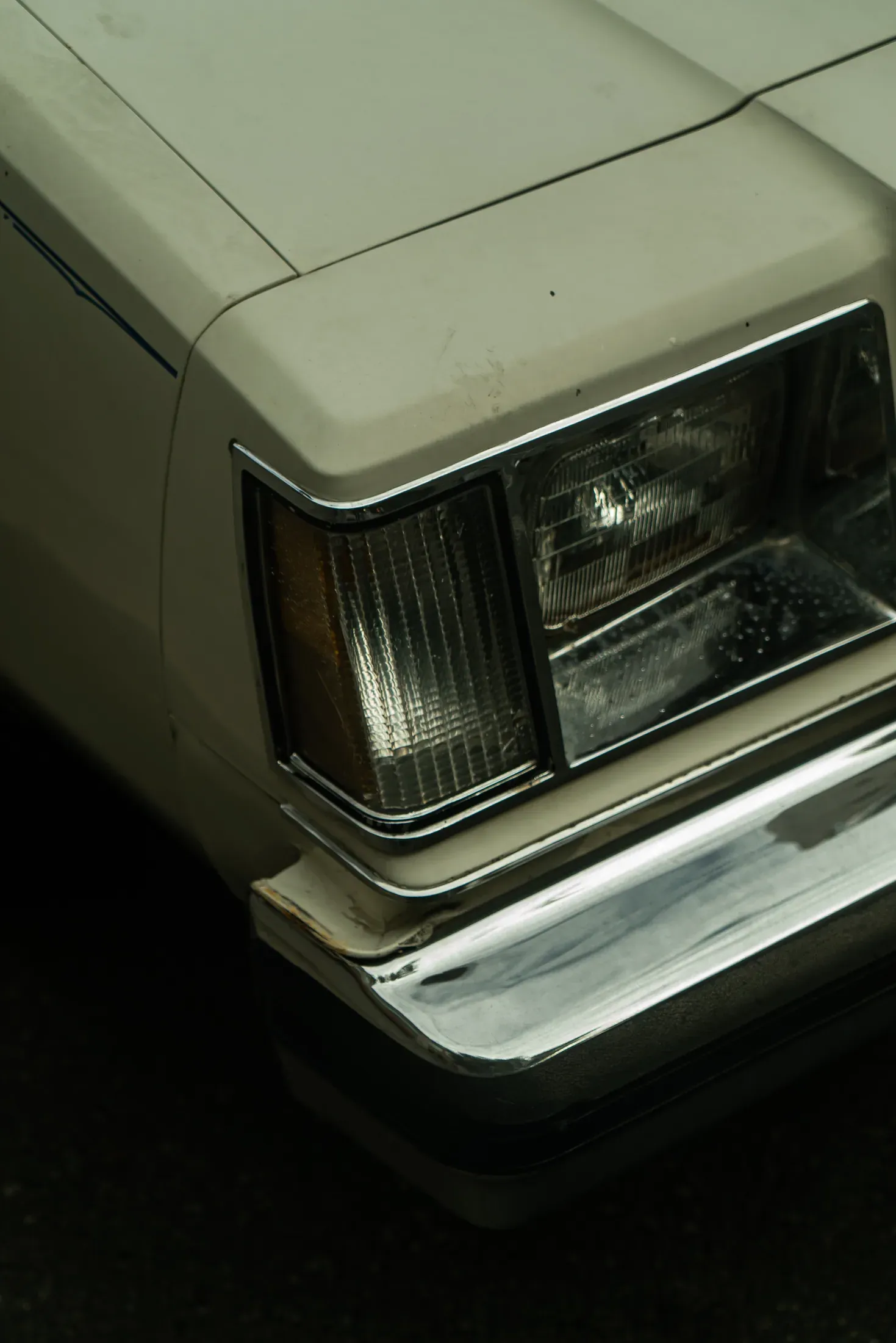 The front corner of a vintage car at the curb.