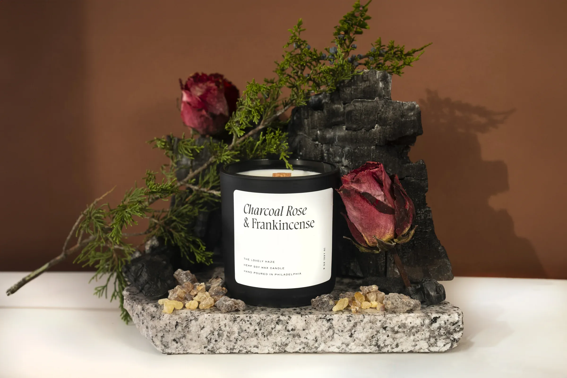 Charcoal Rose and Frankincense candle styled with natural materials.