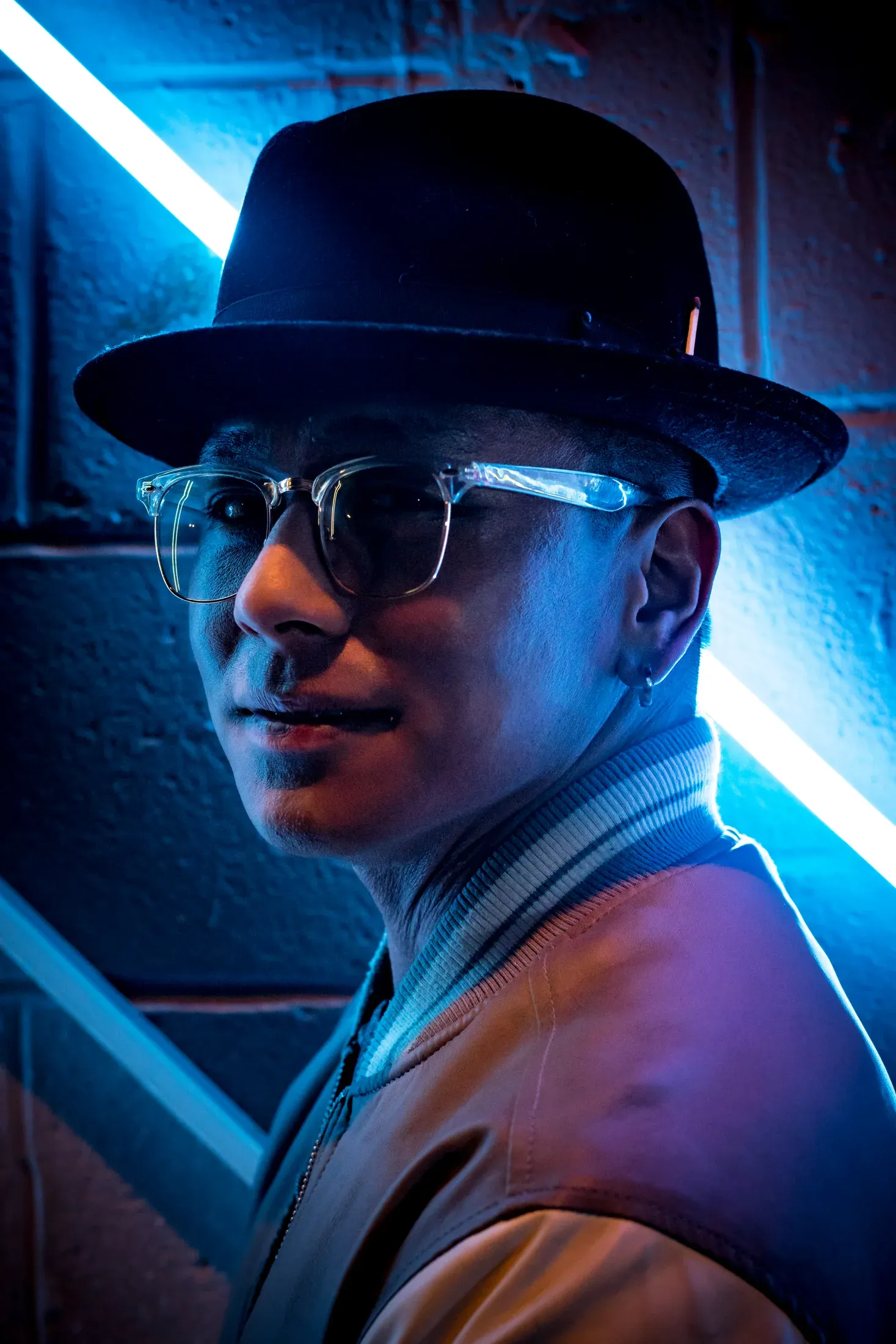 Portrait of a man in a wide-brim hat illuminated by blue neon light.