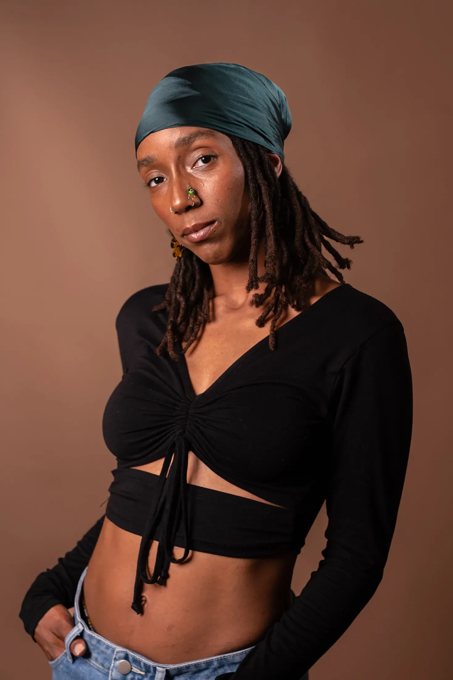 Studio portrait of a woman in black against a warm backdrop.