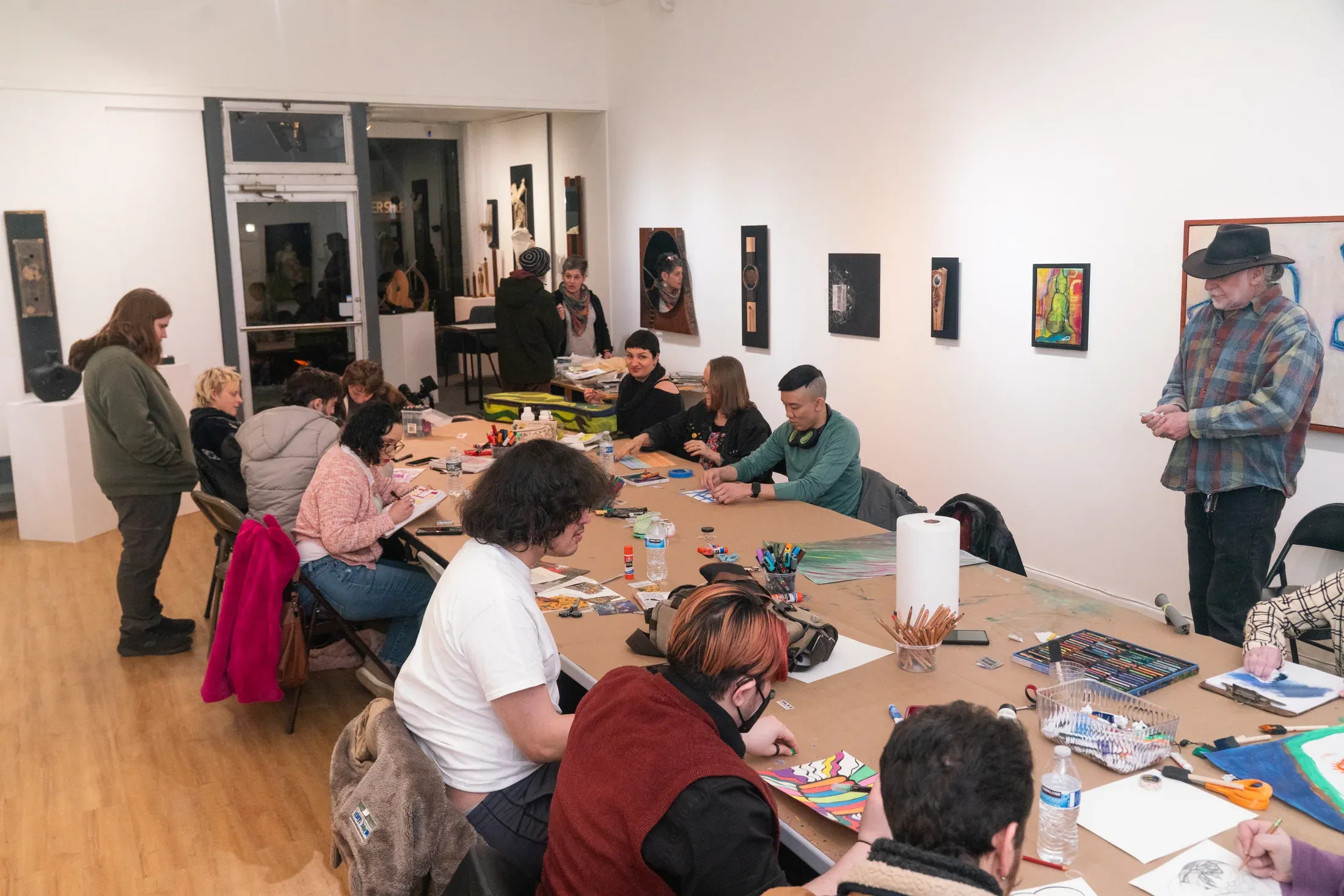 Artists gathered around a long worktable inside A Mano Gallery.