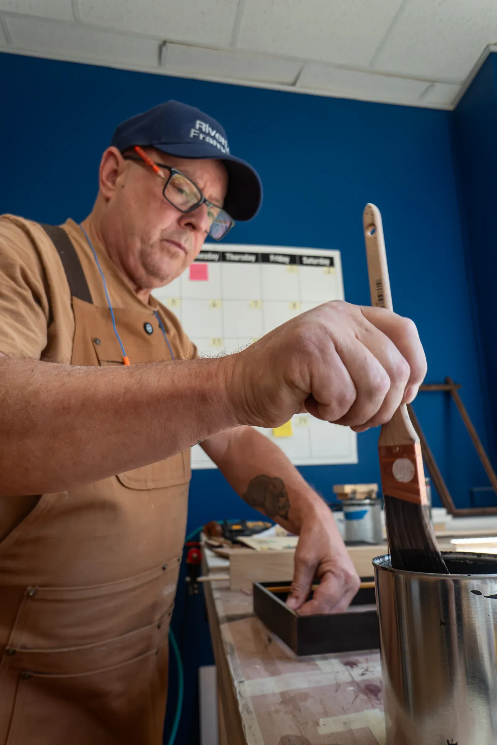A woodworker applying finish by hand in the workshop.