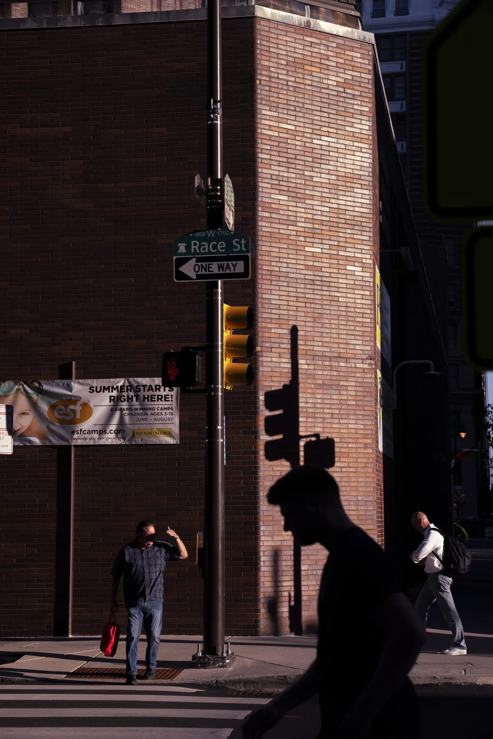 Pedestrians and traffic-light shadows crossing Race Street in Philadelphia.